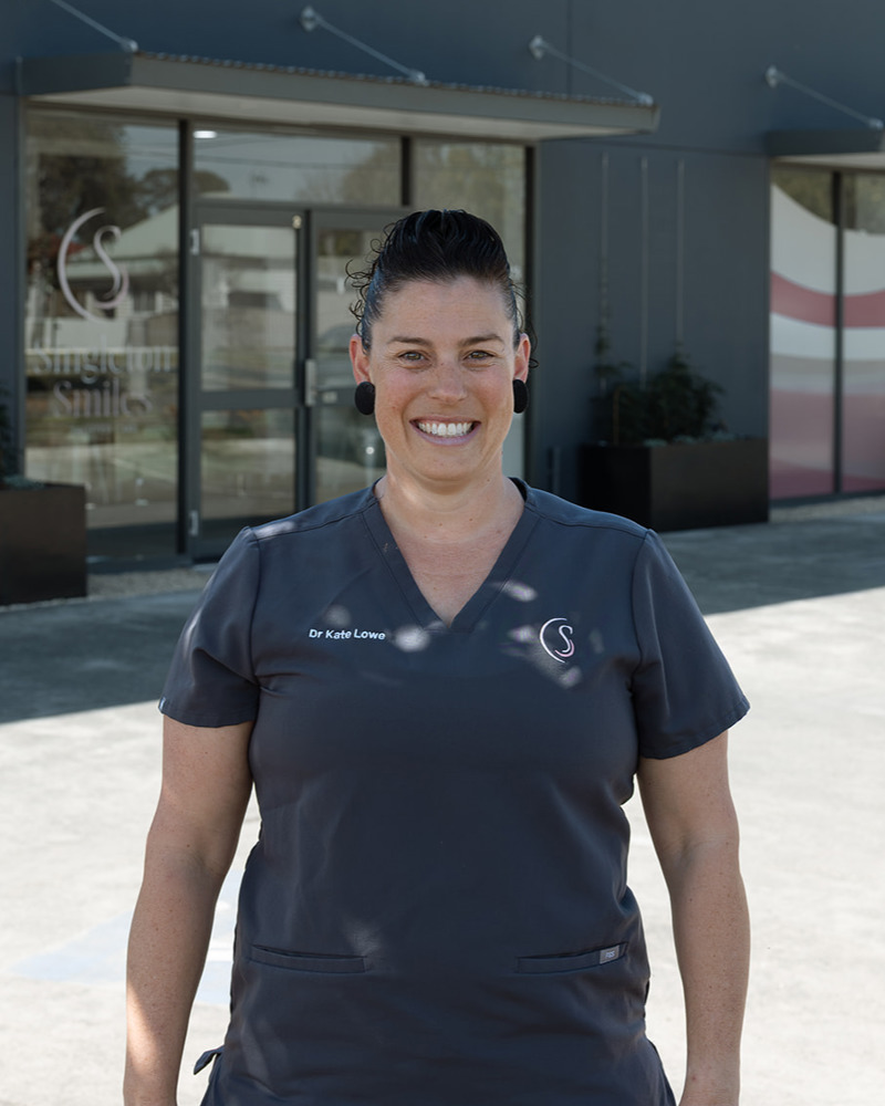Dr Kate Lowe, principal dentist and co-owner of Singleton Smiles, smiling warmly in dark grey scrubs